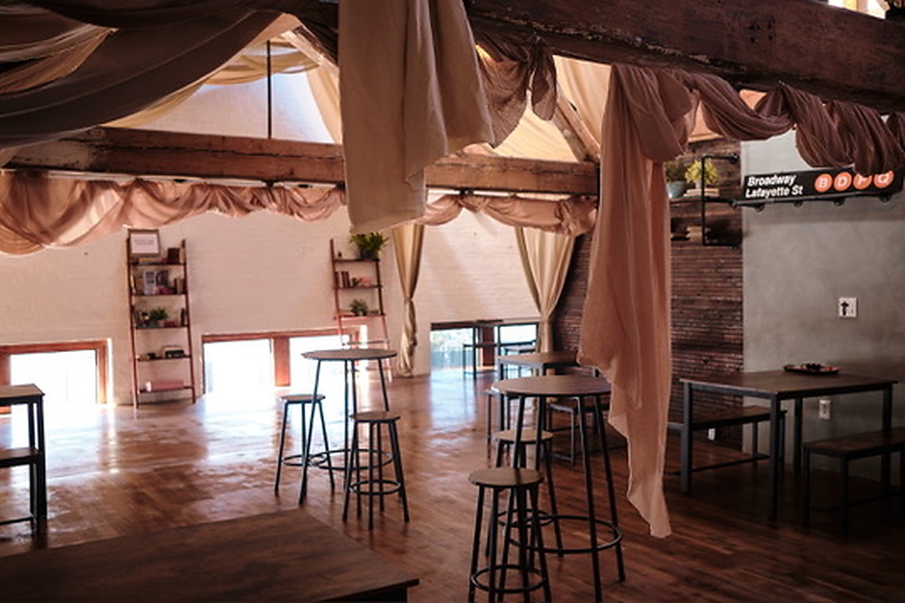 Wide view of the upper brwnbox event space with draped beams, wood floors and flexible tables